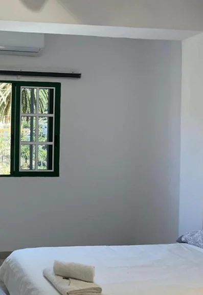 Dormitorio con ventana de carpintería verde y aire acondicionado